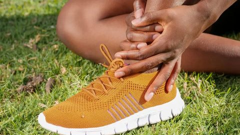 An athlete sitting on the grass holding a sprained ankle, representing the most common sports injuries.