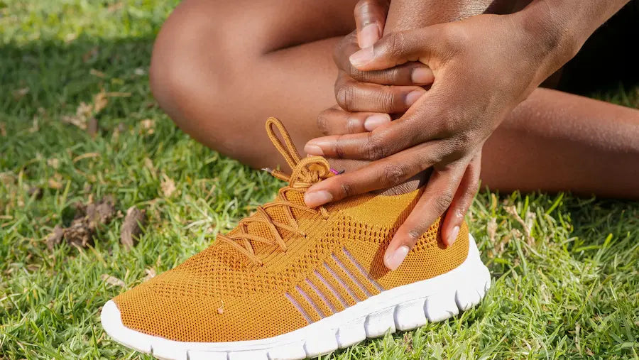 An athlete sitting on the grass holding a sprained ankle, representing the most common sports injuries.